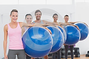 Fitness class holding exercise balls at fitness studio