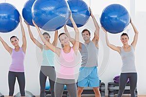 Fitness class holding up exercise balls at fitness studio