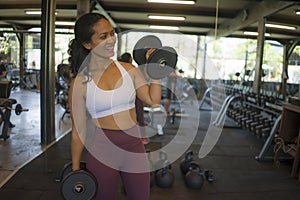 Fitness club lifestyle portrait of young attractive and happy athletic Asian Indonesian woman training hard at gym lifting weight