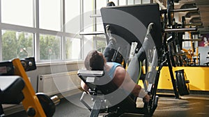 Fitness club - muscular man exercising on leg press machine