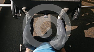 Fitness club - muscular man exercising on leg press machine - close up