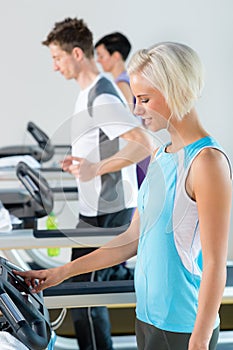 Fitness club woman set-up level on running belt photo