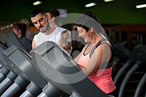 Fitness coach assisting his client on treadmill