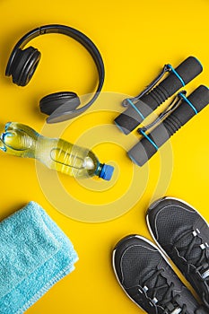 Fitness concept. Black sports shoes, headphones, dumbbell and bottle of water