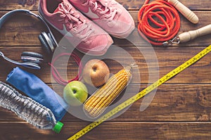 Fitness concept with Exercise Equipment and Healthy food on wooden background
