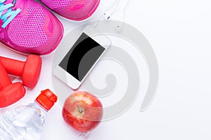 Fitness concept with mobile phone, towel, shoes, dumbbells, red apple and woman sport footwear over white background. View from ab