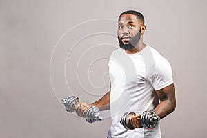 Fitness concept. Portrait of a happy african american black man with dumbbells isolated over grey background