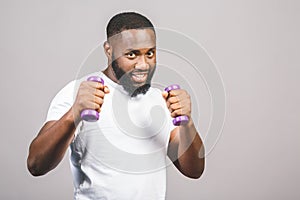 Fitness concept. Portrait of a happy african american black man with dumbbells isolated over grey background