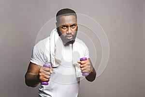 Fitness concept. Portrait of a happy african american black man with dumbbells isolated over grey background