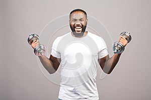 Fitness concept. Portrait of a happy african american black man with dumbbells isolated over grey background