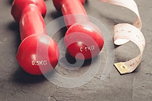 fitness concept with red dumbbells and measuring tape/ fitness concept with red dumbbells and measuring tape on a dark background