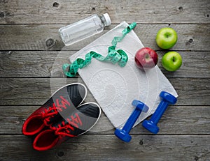 Sneakers dumbbells bottle of water apple and measure tape