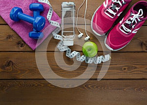 Sneakers dumbbells bottle of water apple and measure tape