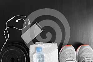 Fitness concept. Sport equipment. Sneakers sport shoes, towel, bottle of water, earphones, dumbbells and phone on black backgrou