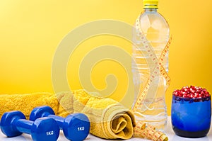 Fitness concept with towel, bottle, centimeter and dumbbells