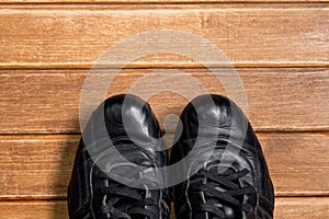 Fitness concepts- athletic shoes on wooden background. Old reliable black leather sneakers.