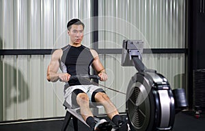 Fitness-conscious man passionately engaging in indoor rowing, in well-equipped gym