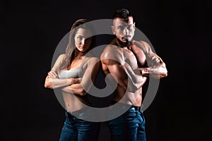 Fitness couple on a black background looking to the camera with crossed arms