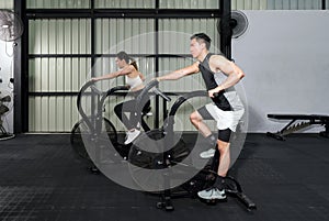 Fitness Couple Cycling on Stationary Bikes in Health Club