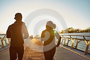 Fitness couple exercising in the early morning. Back view of young sporty african couple jogging, running together on