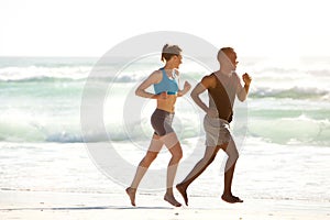 Fitness couple running along the sea on beach