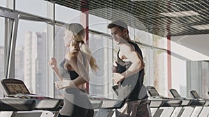 Fitness couple running on treadmill machine in gym club together