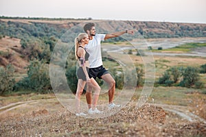 Fitness couple standing on a hill and looking at something