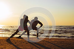 Fitness couple stretching in sunset