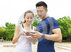 fitness couple wearing sportswear and looking at smartphone