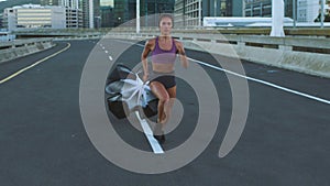 Fitness, crossfit and professional woman athlete running with parachute resistance training in urban city street. Sports