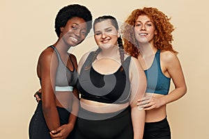 Fitness. Different Ethnicity Models Portrait. Smiling Diversity Women In Fitness Clothes Posing On Beige Background.