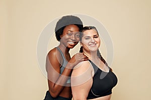 Fitness. Different Ethnicity Women Portrait. Caucasian And African Models In Fitness Clothes Posing On Beige Background.