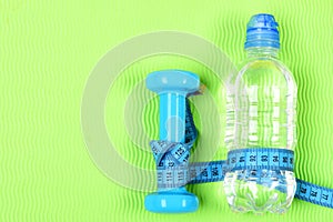 Fitness dumbbell, centimeter and bottle of water.