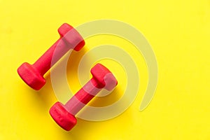 Fitness dumbbell sports equipment top view, yellow color background.