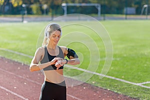 Fitness enthusiast checking smartwatch during track workout in sports gear