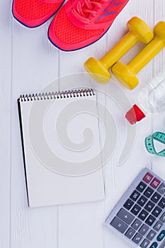 Fitness equipment, calculator and paper notepad.