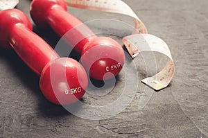 Fitness equipment on a dark background/fitness equipment with red dumbbells and measuring tape. Selective focus