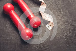 fitness equipment on a dark background/ fitness equipment with red dumbbells and measuring tape. Top view and copy space