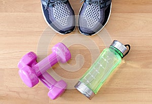 Fitness equipment, Dumbbell shoes, water bottles on wooden floor.Health and Fitness Concepts