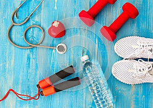 Fitness equipment gym workout and fresh water with heart and medical stethoscope on the blue background.