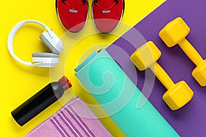 Fitness equipment. Sport training concept. Dumbbells on purple roll mat on yellow background. Healthy lifestyle. Flat lay. Red