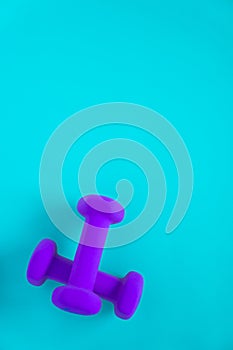 Fitness equipment with womens purple weights/ dumbbells isolated on a light sky blue background with copyspace