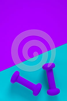 Fitness equipment with womens purple weights/ dumbbells isolated on a light sky blue and purple background with copyspace