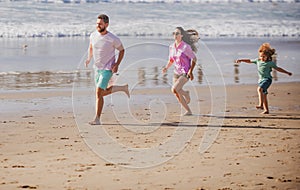 Fitness family running on the beach. Happy mother father with child son, having fun during summer holiday. Family