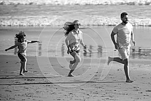 Fitness family running on the beach. Happy mother father with child son, having fun during summer holiday. Family