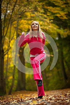 Fitness fit woman blond girl doing exercise in autumnal park. Sport.