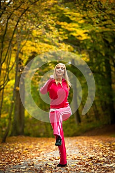 Fitness fit woman blond girl doing exercise in autumnal park. Sport.