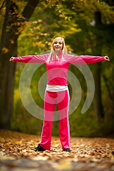 Fitness fit woman blond girl doing exercise in autumnal park. Sport.