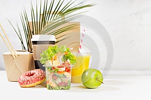 Fitness food set of coffee, orange juice, shrimp salad, noodles in box, donut, apple, packet in white interior, palm leaf. Mockup.