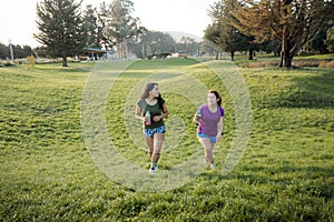 Fitness Friends: Two Latin Women Walking on the grass in the Park after running exercise at sunset.